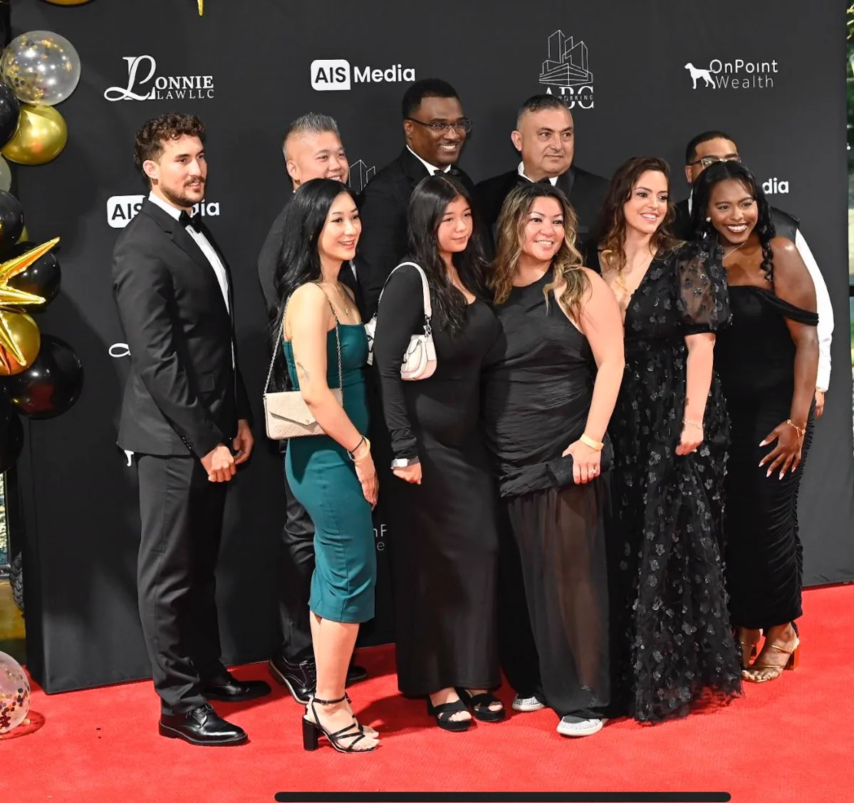 A large group of guests gathers at the 2025 gala sponsor backdrop